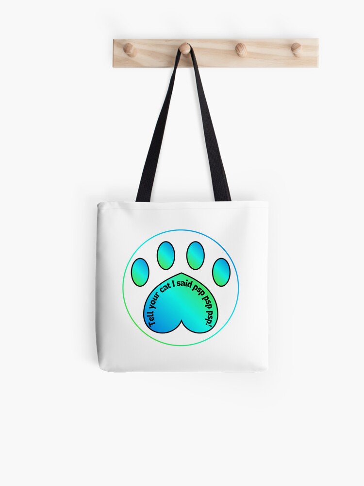Photo of a white tote bag with black handles and a paw print in blue to green gradient with the words "Tell your cat I said psp psp psp!"