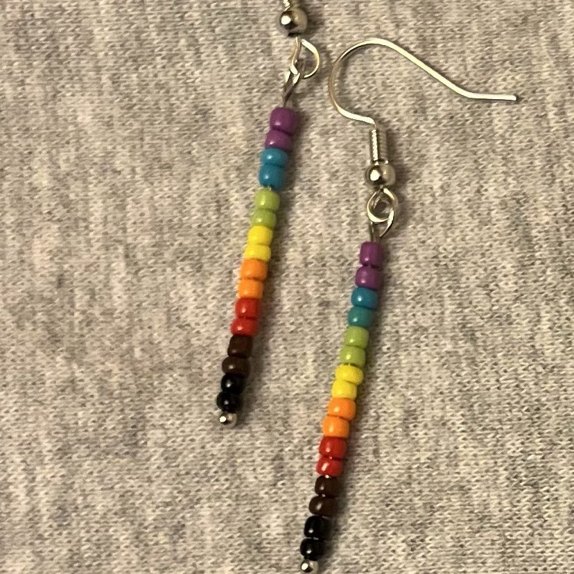 One pair of earrings made of size 12.0 opaque glass seed beads in the progressive rainbow colours: purple, blue, green, yellow, orange, red, brown, and black.